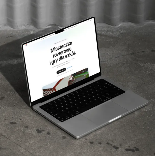 Laptop na betonowym blacie ze stroną główną strefygier.pl: miasteczka rowerowe i gry dla szkół